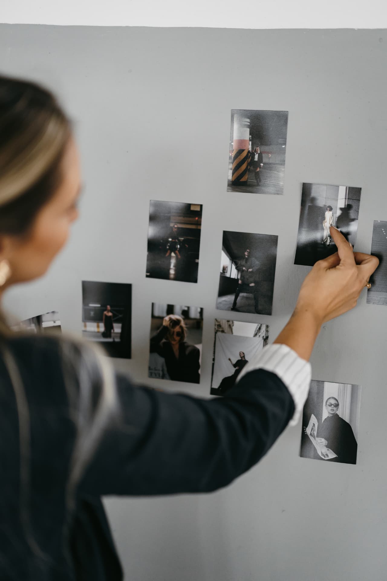 Mão escolhendo fotos impressas presas na parede